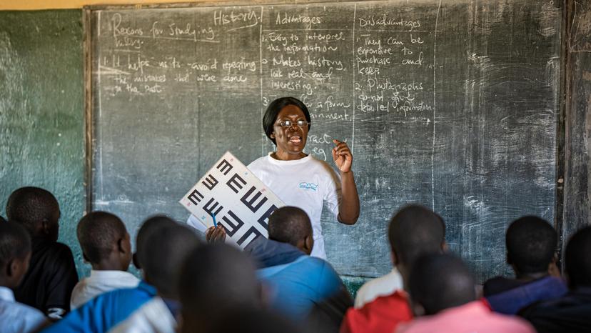 Woman with vision test chart in front of school class