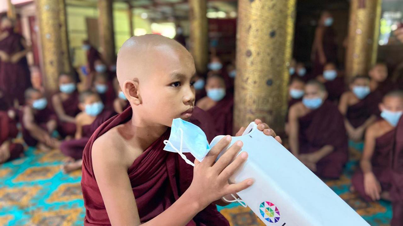 Buddhist young monk holding Kaleidos autorefractometer