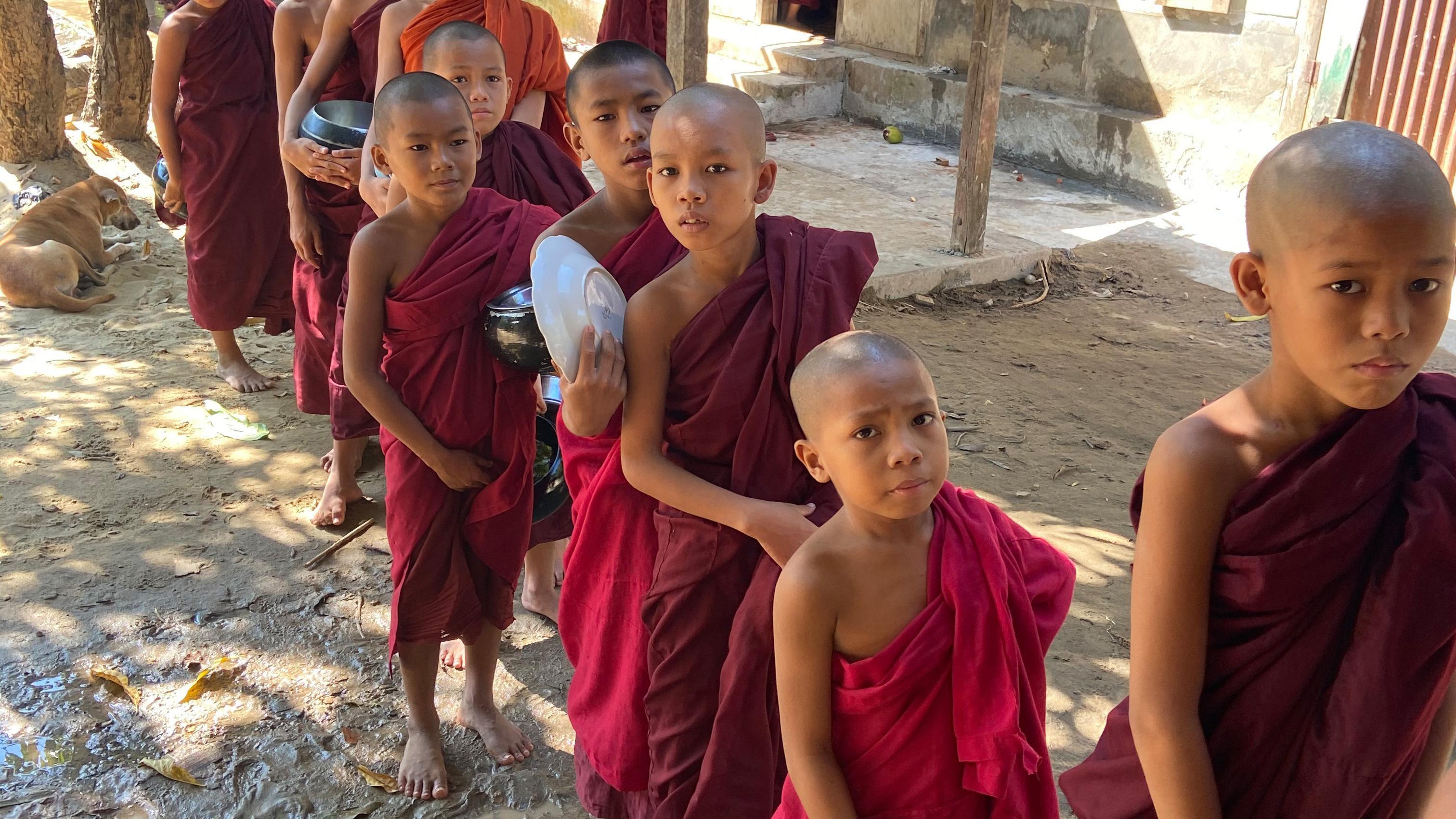 Junge Buddhisten warten auf das Mittagessen, stehen in einer Reihe
