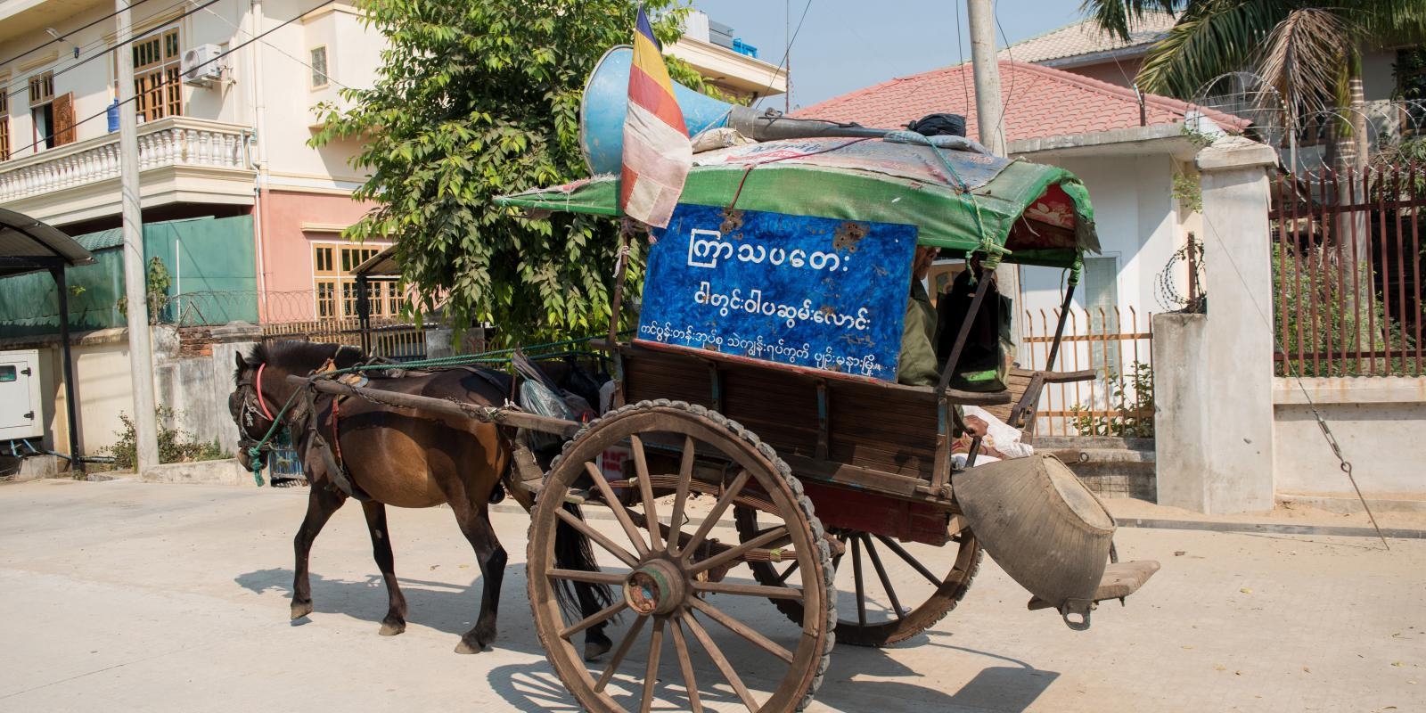Simple horse-drawn cart with advertising poster for GoodVision Myanmar and loudspeaker